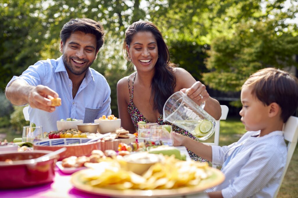 Family Eating Outdoor Meal In Garden At Home Together