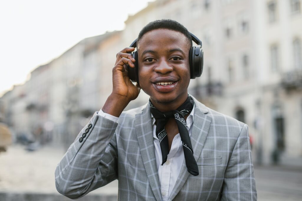 Happy african man in headphones listening music on street
