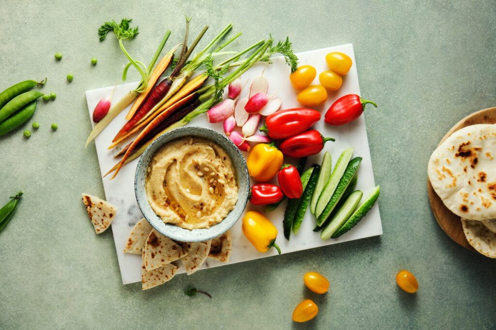 Homemade hummus with spices, pine nuts and rainbow veggie platter