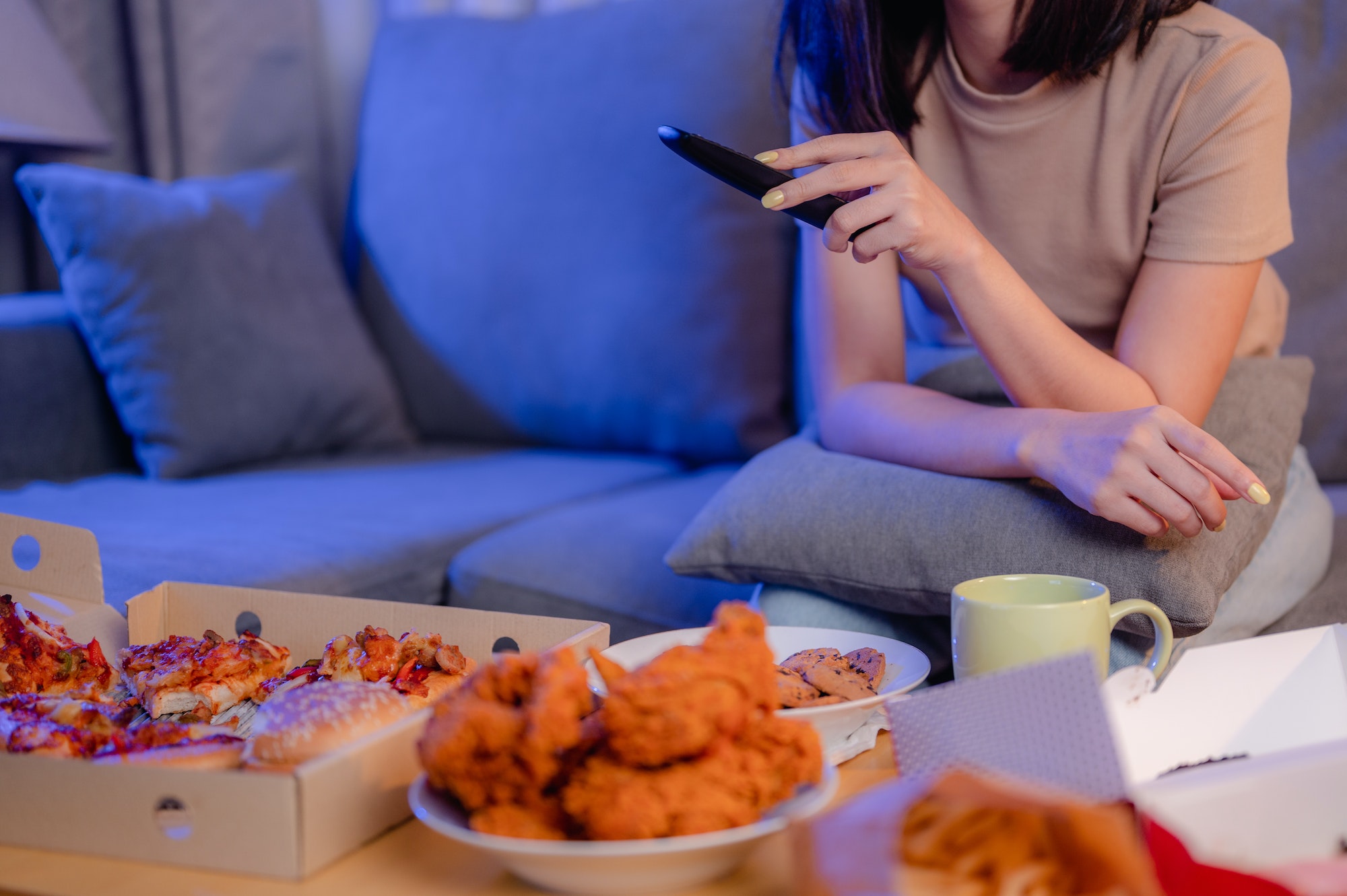 Hungry young woman eating junk food Fried Chicken and French Fries for dinner by ordering delivery