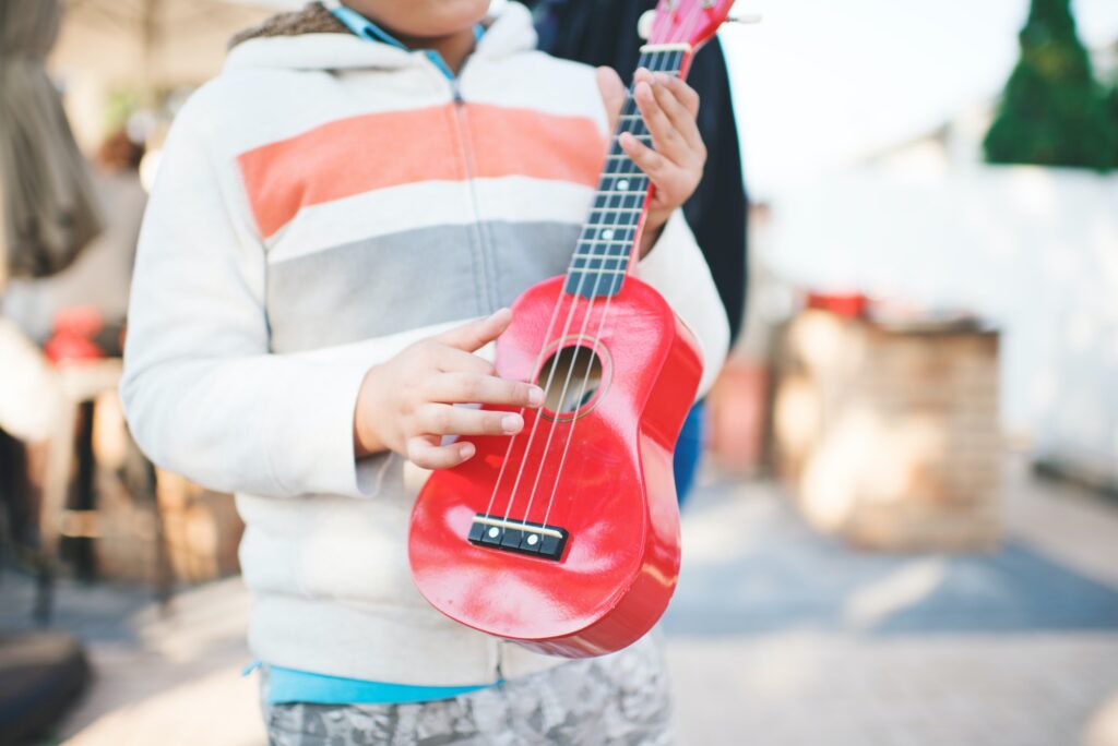Kid playing ukulele instrument