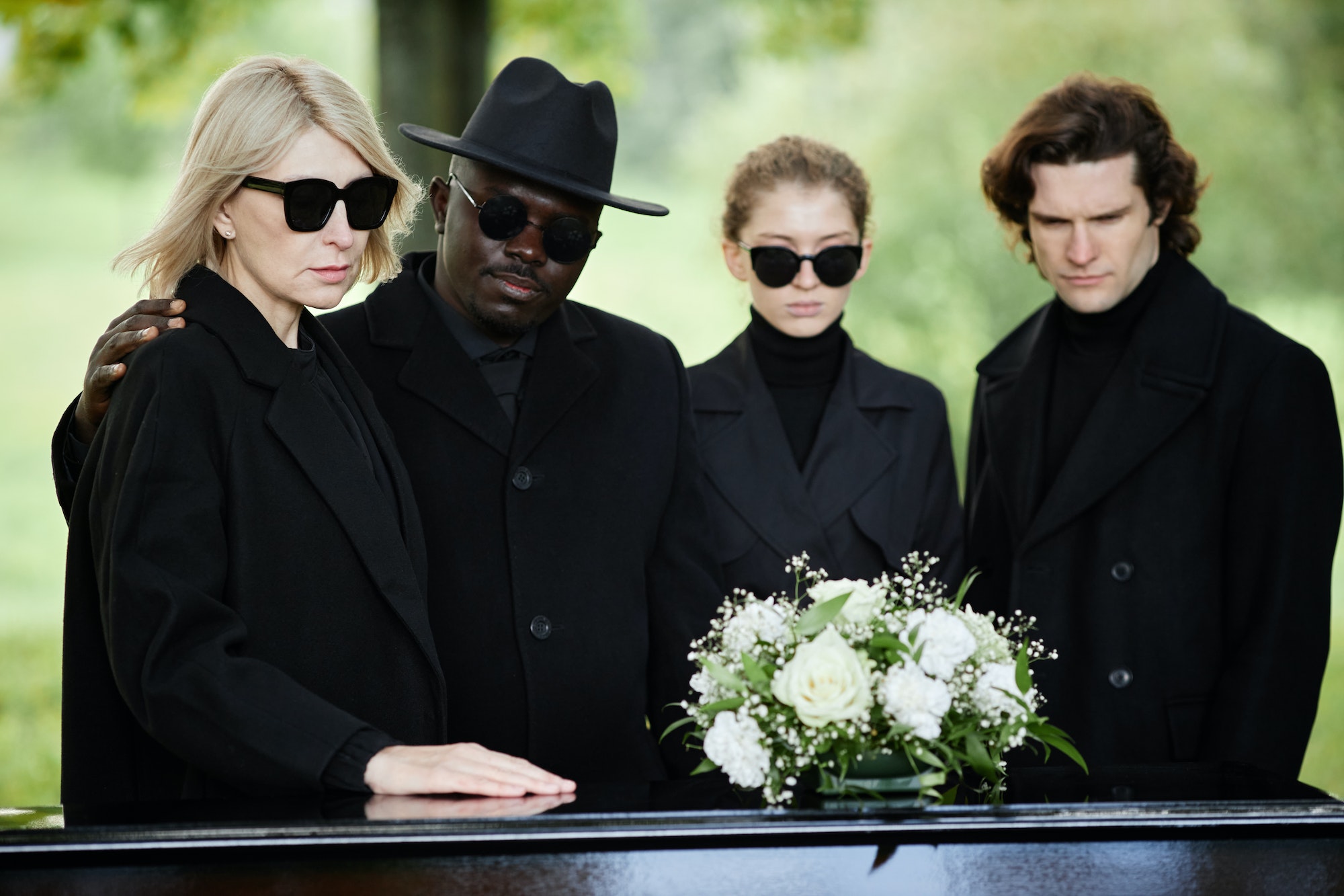 People standing by coffin at funeral ceremony