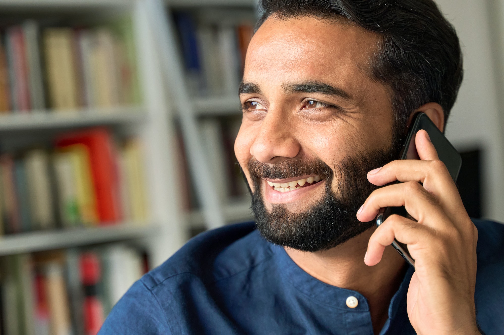 Smiling indian business man talking on phone making call, closeup.