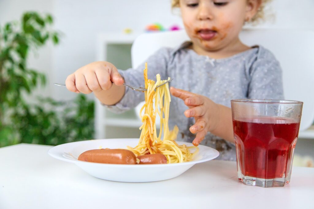 The child eats spaghetti lunch. Selective focus.