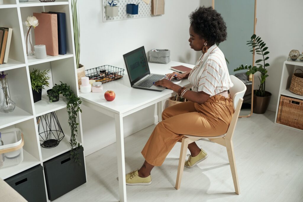 Young contemporary businesswoman networking by desk at home